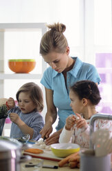 Mutter und zwei Kinder bereiten in der Küche eine Mahlzeit zu - WESTF00217