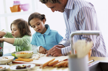 Vater mit Kindern (4-7) bei der Zubereitung einer Mahlzeit - WESTF00205