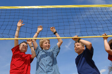 Boys (6-9) at volleyball net, low angle view - CRF00873