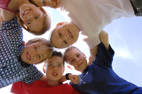 Children (6-9) in huddle, low angle view, portrait - CRF00871