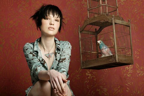 Junge Frau mit Papagei im Käfig, Porträt, Retro-Stil, lizenzfreies Stockfoto