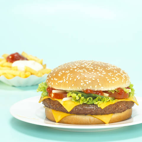 Cheeseburger mit Pommes frites, Fokus auf Hamburger, Nahaufnahme, lizenzfreies Stockfoto