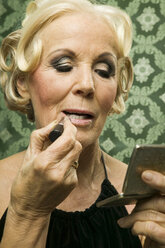 Senior woman painting lips - WEST00351