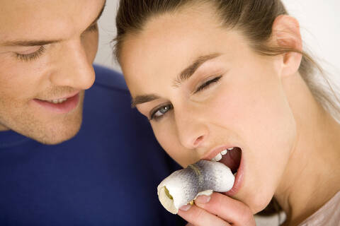 Junges Paar, Frau isst Rollmops, lizenzfreies Stockfoto