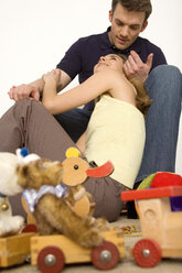 Junges Paar sitzt mit Spielzeug auf dem Boden - WESTF00461