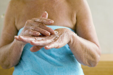 Ältere Frau, in ein Handtuch gewickelt, cremt sich mit den Händen ein, Mittelteil, Nahaufnahme - WESTF00654