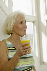 Senior woman holding glass of juice, smiling, close-up - WESTF00619