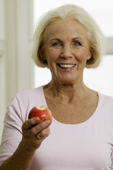 Ältere Frau isst Apfel, lächelnd, Nahaufnahme, Porträt - WESTF00616