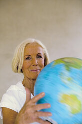 Senior woman spinning globe, close-up - WESTF00613