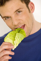 Junger Mann isst Salatblatt, Nahaufnahme - WESTF00523