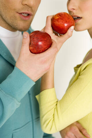 Junges Paar mit Apfel in der Hand, Mittelteil, Nahaufnahme, lizenzfreies Stockfoto