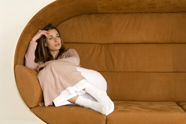 Young woman relaxing on sofa, looking away - WESTF00535