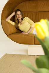 Junge Frau entspannt sich auf dem Sofa und schaut weg - WESTF00530