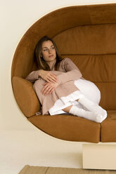 Junge Frau entspannt sich auf dem Sofa und schaut weg - WESTF00525