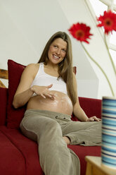 Schwangere Frau beim Eincremen des Bauches - BMF00294