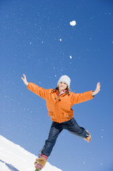 Austria, girl (12-13) in snow balancing on one leg with arms outstretched, smiling, portrait - WESTF00732