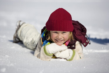 Österreich, Mädchen (6-7) im Schnee liegend, lächelnd, Nahaufnahme, Porträt - WESTF00725