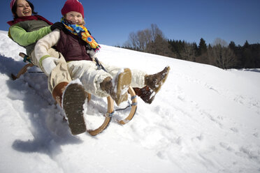 Austria, girls (6-17) sledging on snow covered slope, smiling, low angle view - WESTF00721