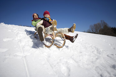 Österreich, Mädchen (6-17) beim Schlittenfahren auf verschneitem Hang, lächelnd, Tiefblick - WESTF00720