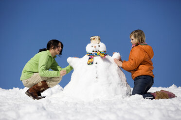 Österreich, Mädchen (12-17) bauen Schneemann, Seitenansicht - WESTF00712