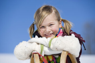 Austria, girl (6-7) leaning on sledge, smiling, close-up, portrait - WESTF00688