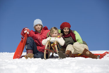 Österreich, Mädchen (6-17) sitzend mit Schlitten im Schnee, lächelnd, Porträt - WESTF00681