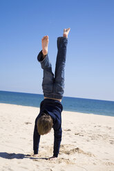 Portugal, Algarve, boy (8-11) doing handstand on beach, rear view - MSF01931