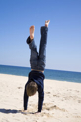 Portugal, Algarve, Junge (8-11) macht Handstand am Strand, Rückansicht - MSF01931