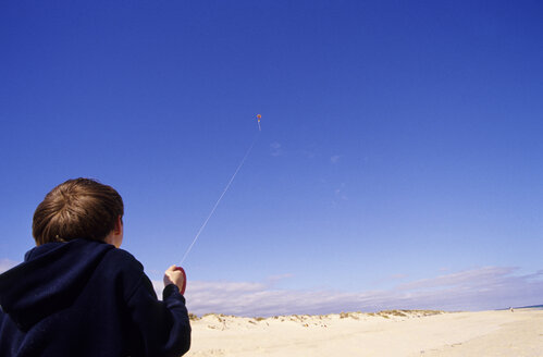 Portugal, Algarve, Junge (8-11) lässt am Strand Drachen steigen, Rückansicht - MSF01924