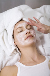 Kosmetikerin trägt eine Gesichtsmaske auf das Gesicht einer jungen Frau auf, Ansicht von oben - MAEF00046