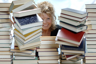 Woman pushing pile of books, smiling, portrait - CRF00910
