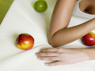 Woman lying on bed with apples, mid-section - WESTF00978