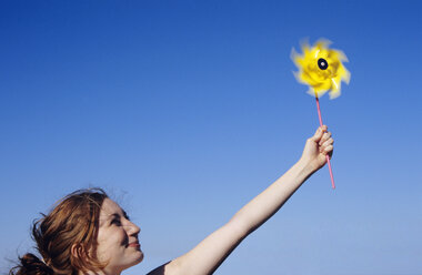 Young woman holding pin wheel into air - WESTF01197