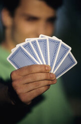 Young man holding playing cards, focus on cards at foreground, close-up - WESTF01190