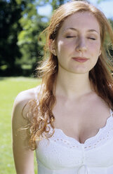 Young woman in white dress standing in garden, eyes closed, close-up - WESTF01151