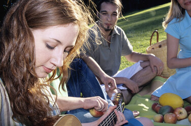 Junge Frau spielt Gitarre für Freunde im Garten, Nahaufnahme - WESTF01093