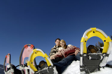 Junges Paar, das mit Schneeschuhen im Schnee sitzt, Tiefblick - WESTF00933