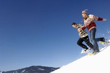 Junges Paar im Schnee, bergab laufend - WESTF00925