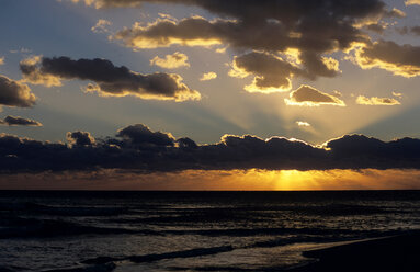 Italien, Apulien, Sonne, die bei Sonnenuntergang durch die Wolken scheint - MOF00108