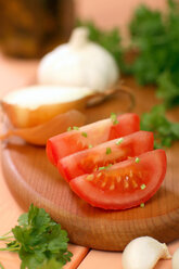Sliced tomato, onion, garlic and parsley on chopping board - WESTF01363