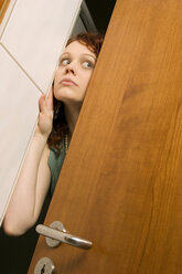 Young woman peeking through door, close-up - CLF00202