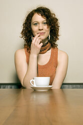 Young woman sitting at table with coffee cup - CLF00158