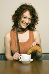 Junge Frau sitzt am Tisch mit Kaffeetasse - CLF00157
