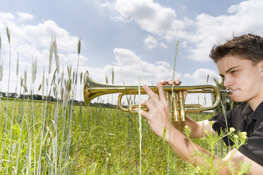 Junger Mann spielt Trompete auf einem Feld, Seitenansicht - 00037MS-U