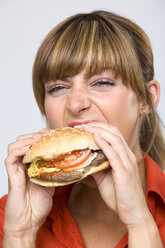 Junge Frau beim Essen eines Hamburgers - WESTF01314