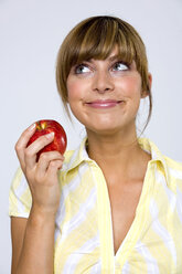 Junge Frau mit Apfel in der Hand, Blick nach oben, Nahaufnahme - WESTF01310