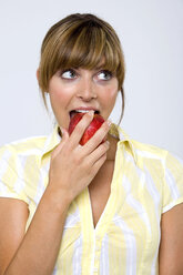Junge Frau beißt in einen Apfel, Blick nach oben, Nahaufnahme - WESTF01309