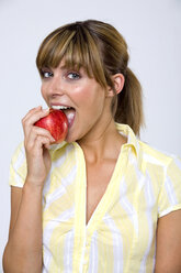 Young woman biting apple, portrait, close-up - WESTF01308