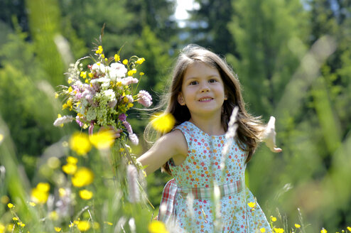 Mädchen (6-7) mit Blumenstrauß auf einer Wiese, lächelnd, Nahaufnahme - WESTF01418