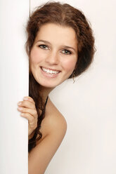 Young woman peeking through door, portrait, smiling - 00092LR-U